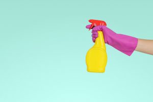 hand with rubber glove holding spray bottle