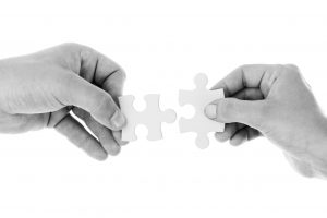 two hands holding puzzle pieces