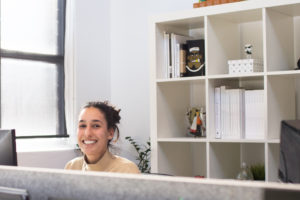 woman in beige turtle next top at desk working